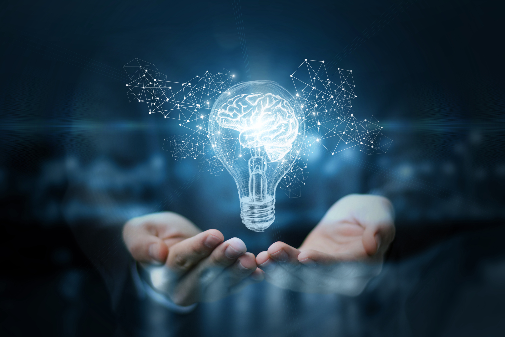 hands presenting illustration of light bulb with brain inside