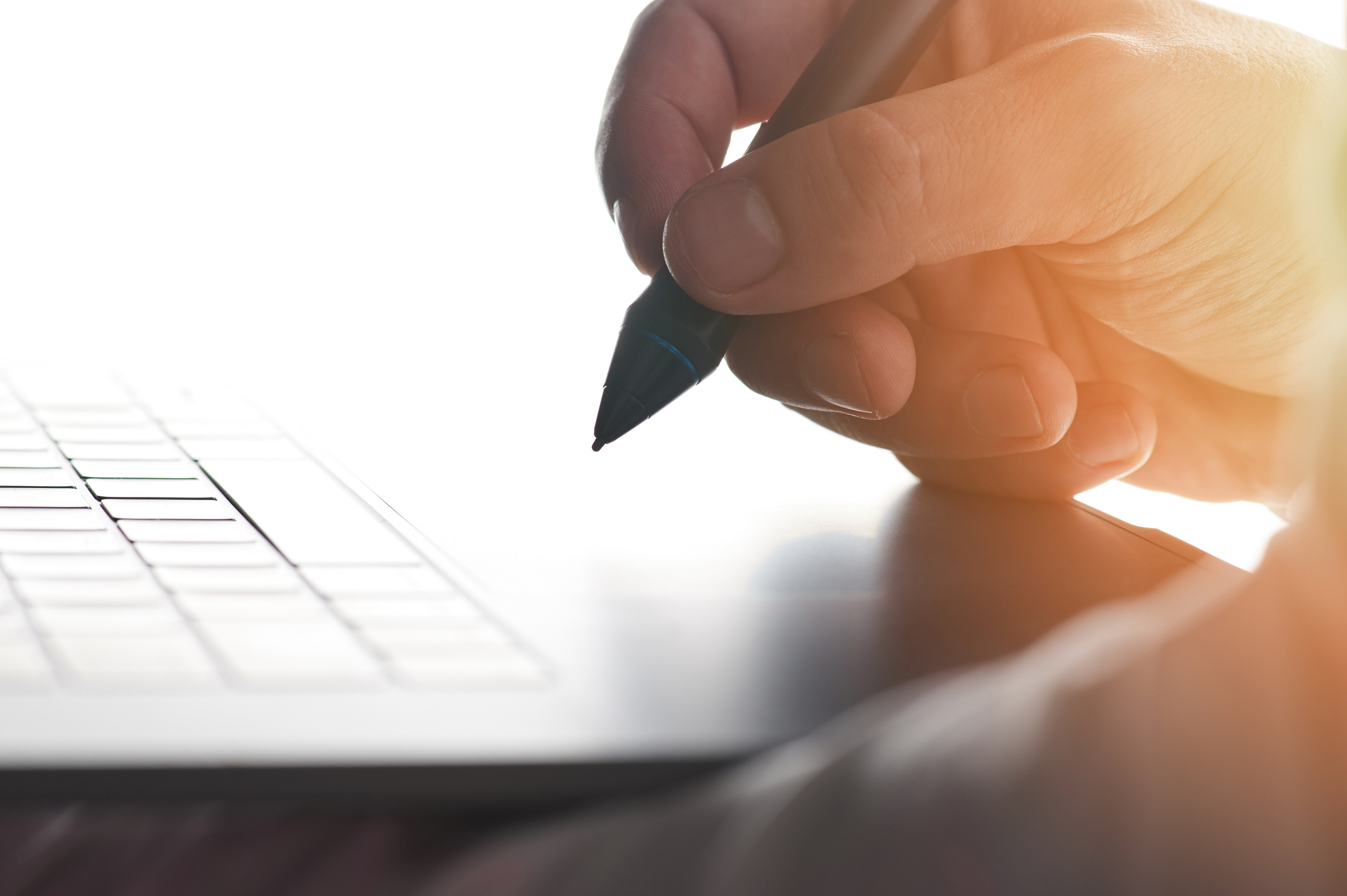 person using electronic pen on laptop trackpad