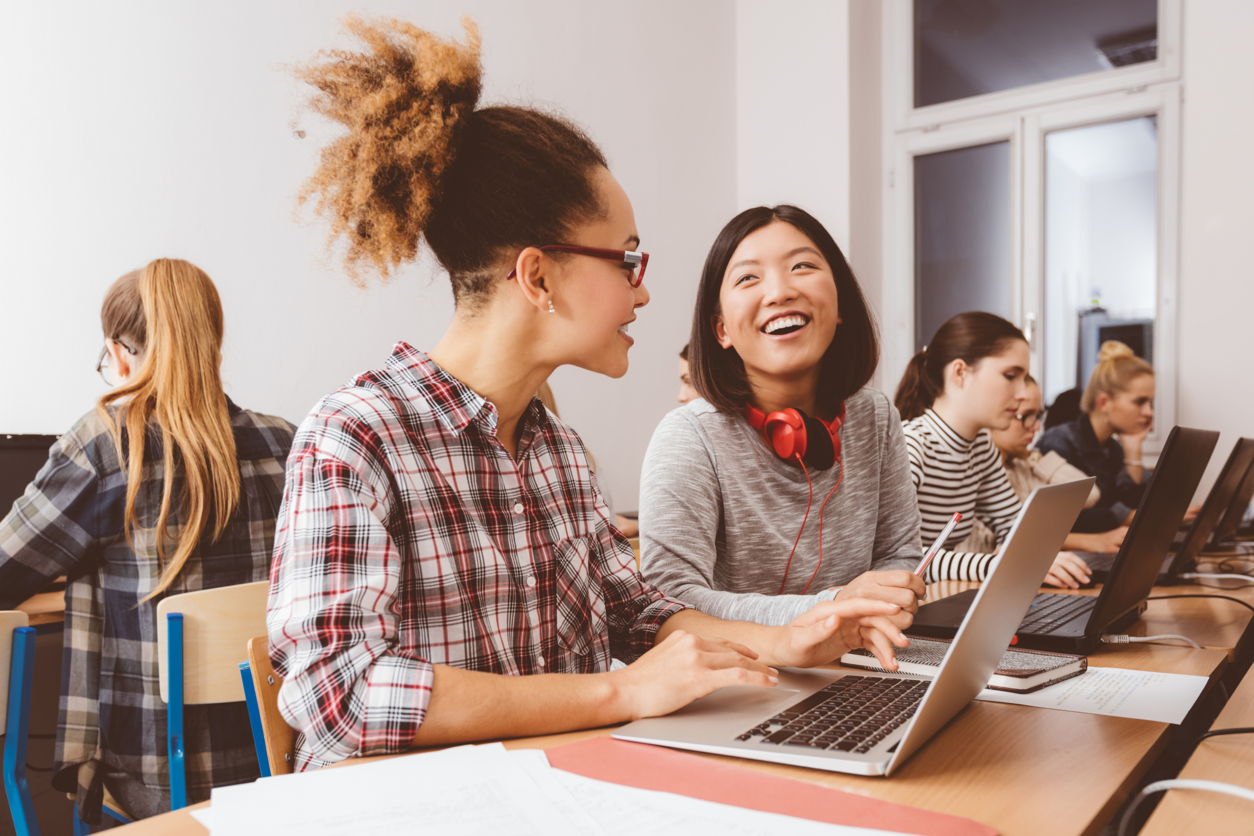 Female university students talking while using laptops