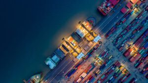 Container Cargo ship and Cargo plane with working crane bridge in shipyard at sunrise